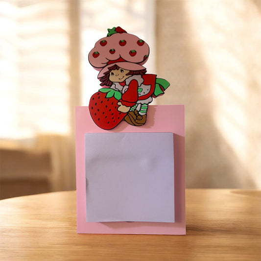 Strawberry shortcake holding strawberry sticky note holder